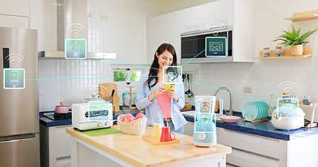 Woman in kitchen, surrounded by IoT appliances