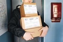 A man holding three small parcels stacked on top of each other