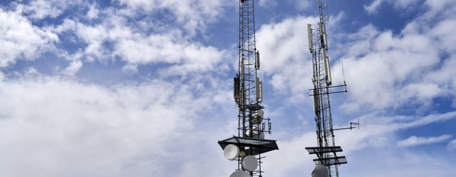 Two telecom towers with cloudy sky in background