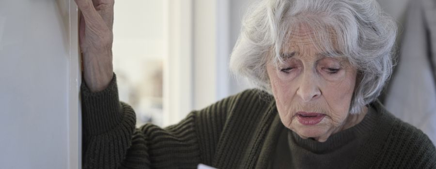 Worried Senior Woman With Bill Turning Down Central Heating